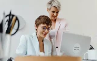 Duas profissionais analisando juntas a tela de um notebook